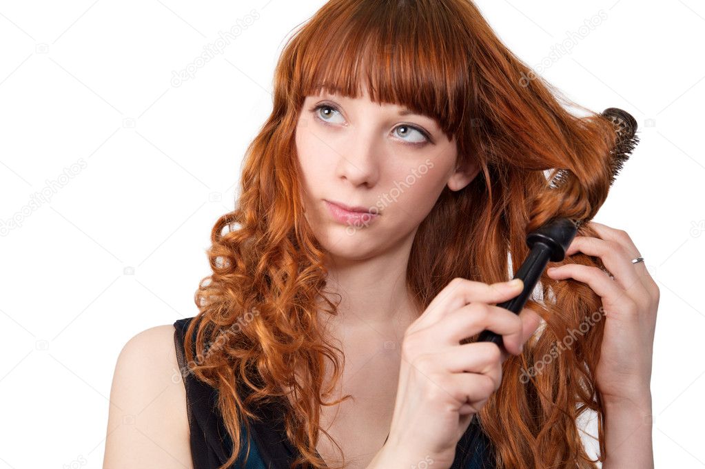 Portrait of a young attractive redhead woman straightening her hair