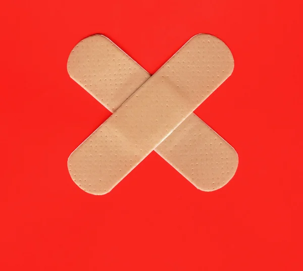 Two plasters forming a cross on red