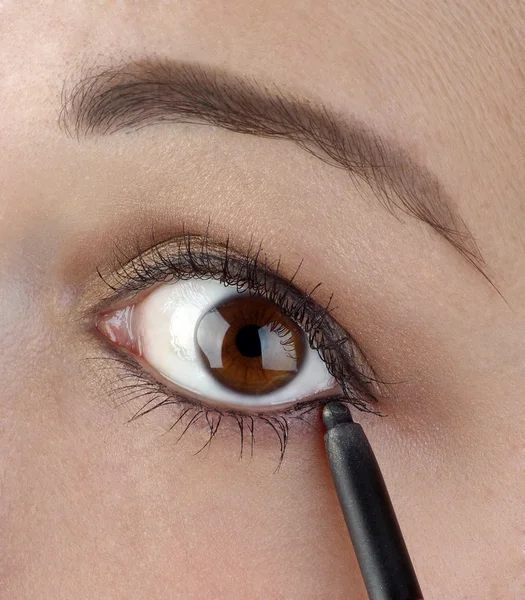 Young women using an eyeliner pencil