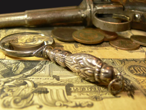 Magnifying glass, coins, gun