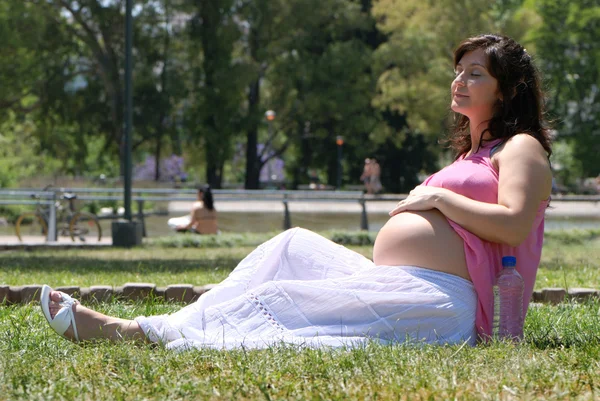 Pregnant happy young woman in park