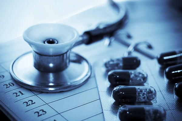 Stethoscope and pills over notebook