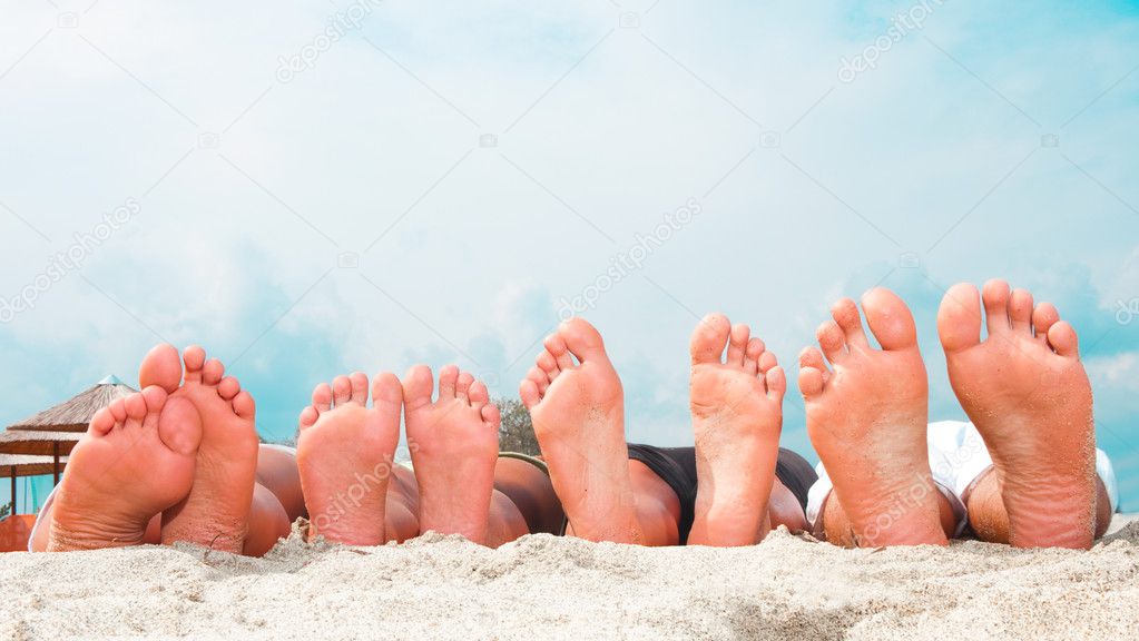 Young couples feet at the sandy beach
