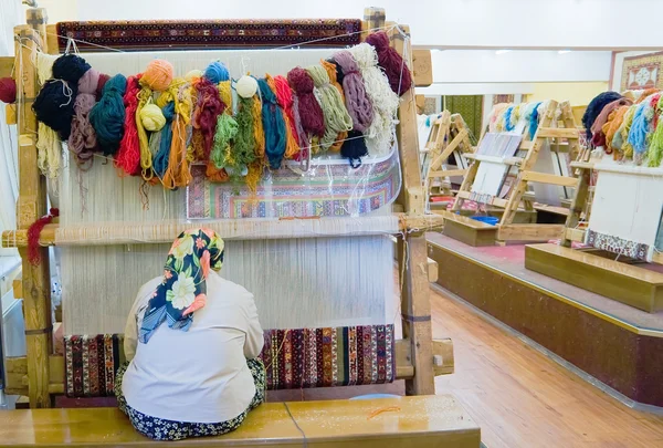 Small weaving mill. The woman behind work - weaving a carpet of silk