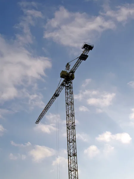 High crane silhouette on blue sky, clouds.