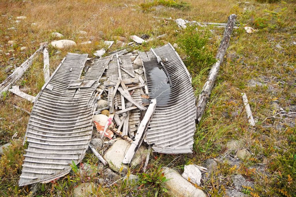 Image of a vintage, broken wooden boat abandoned on the shoreline of 
