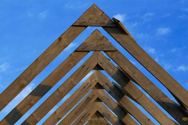 Wooden roof beams under blue skies