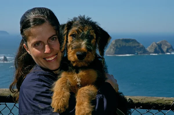 Woman holding a young airedale terrier puppy wit