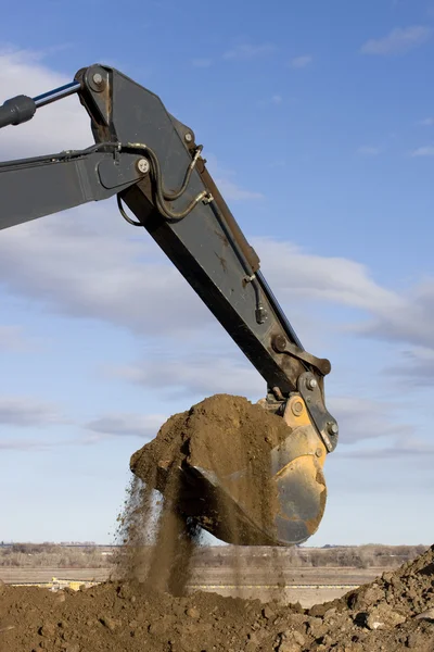 Excavator arm and scoop digging dirt
