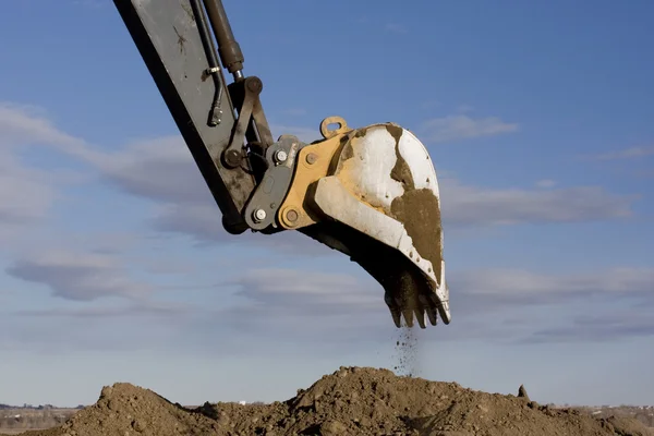 Excavator arm and scoop digging dirt
