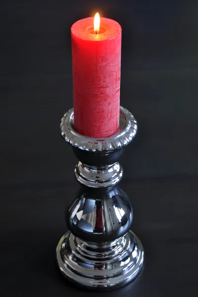 Burning red candle in silver holder