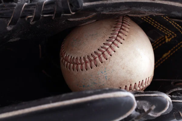 Closeup of old baseball in black glove