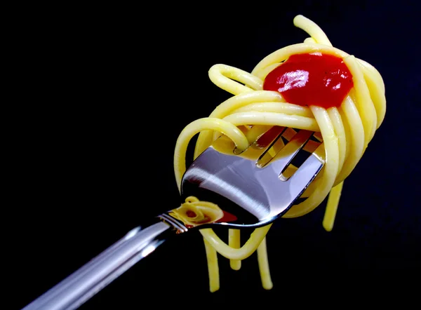 Pasta on fork on black background