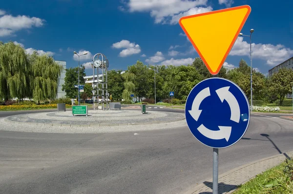 Roundabout with a clock and sign before