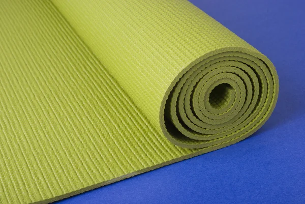 Green yoga mat on blue