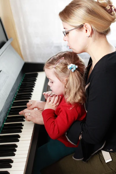 Mother and daughter play piano