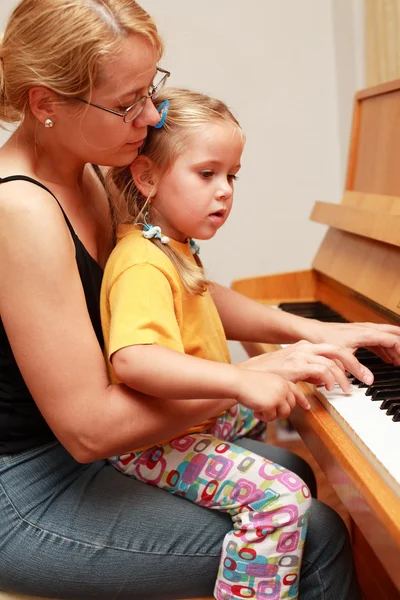 Mother and daughter play piano