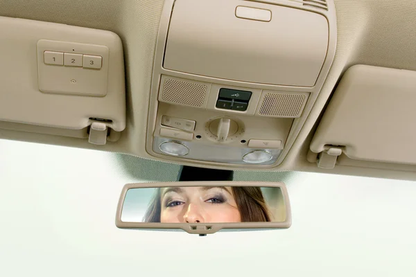 Woman looks on the rear-view mirror