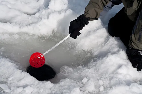 Cleaning out a hole for ice fishing