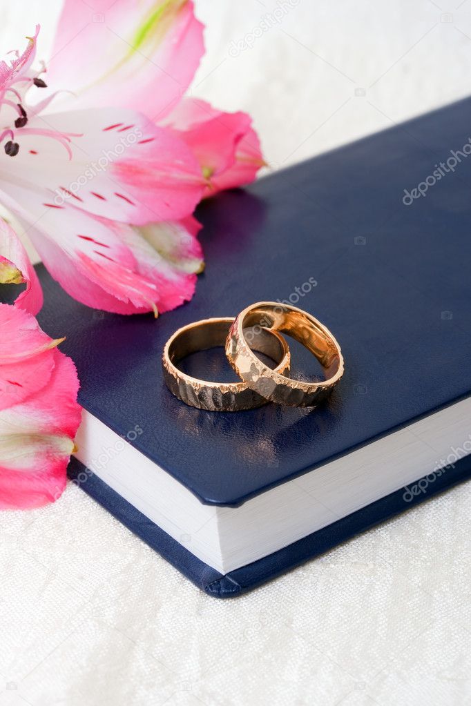 Wedding rings placed on a bible with flowers