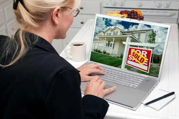 Woman In Kitchen Using Laptop to Research Real Estate