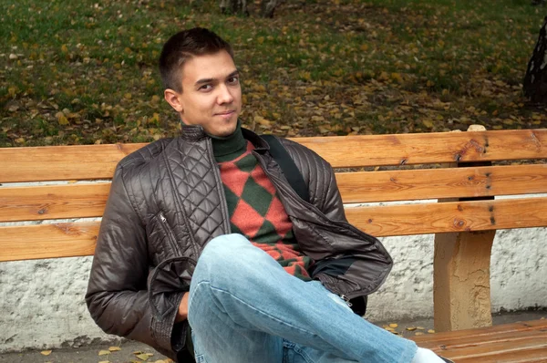 Young man sitting on a bench in park — Stock Photo, Image