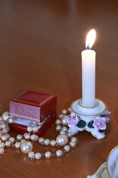 Горящая свеча в фарфоровом подсвечнике и красной коробке подарков — стоковое фото
