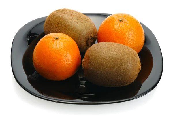 Kiwi och mandarin på en svart plåt — Stockfoto