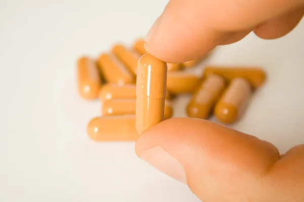 Pill in fingers — Stock Photo, Image