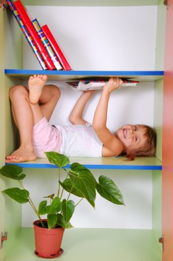 Child reading a book in a bookcase clipart