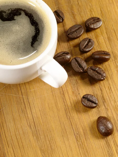 Xícara de café expresso com feijão na madeira — Fotografia de Stock