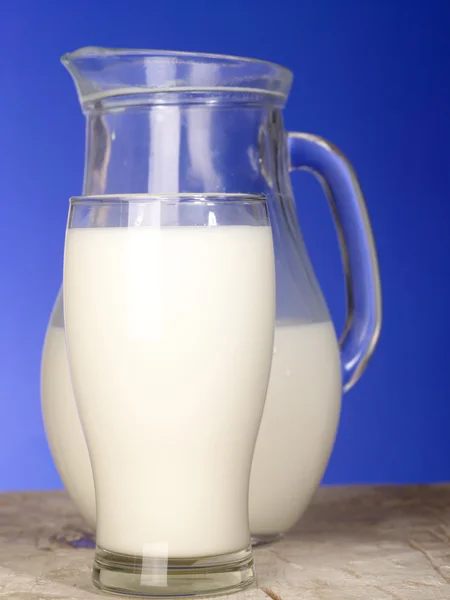 Brocca di latte vicino al vetro sul tavolo — Foto Stock