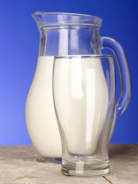 Brocca di latte vicino al vetro sul tavolo arguzia — Foto Stock