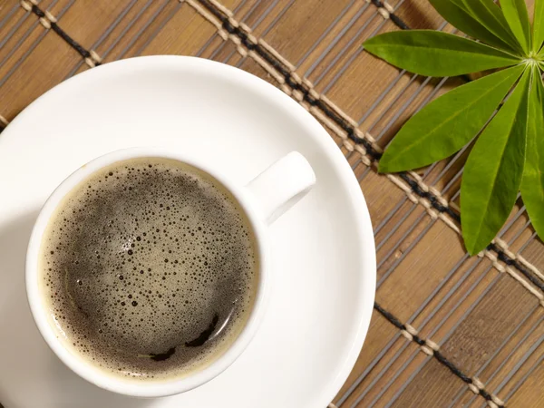 Tazza di caffè sul tavolo con foglia verde — Foto Stock