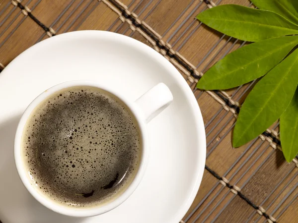 Tazza di caffè sul tavolo con foglia verde — Foto Stock