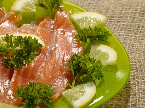 Нарезанная лососевая рыба на зеленой тарелке — стоковое фото