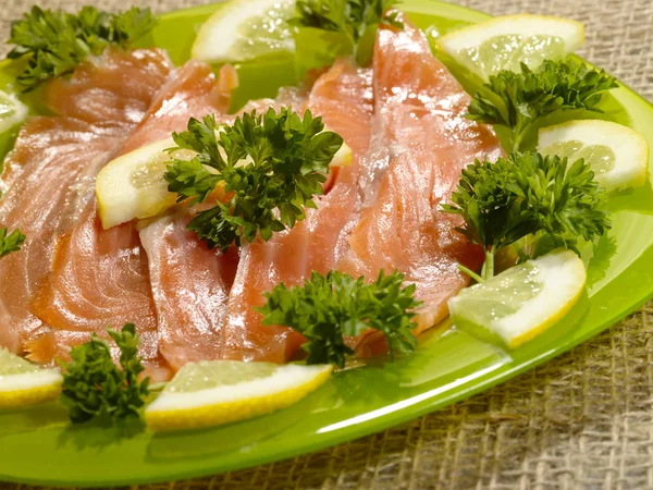 Нарезанная лососевая рыба на зеленой тарелке — стоковое фото