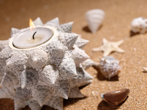 Натюрморт на морском песке со свечой — стоковое фото