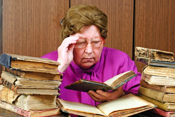 Oude vrouw in bibliotheek met religieuze — Stockfoto