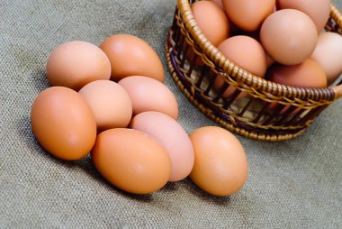 Eggs of brown color in wooden basket clipart