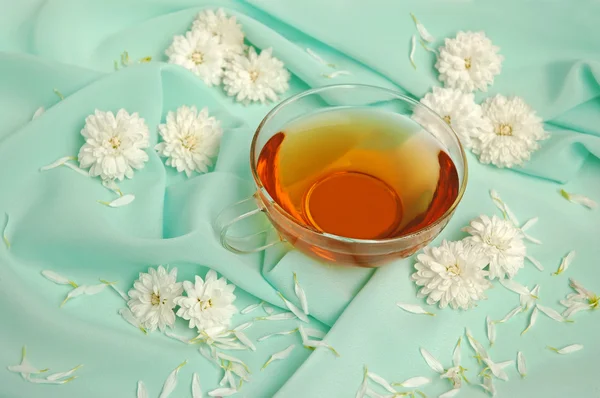 Skleněný šálek čaje a květiny — Stock fotografie