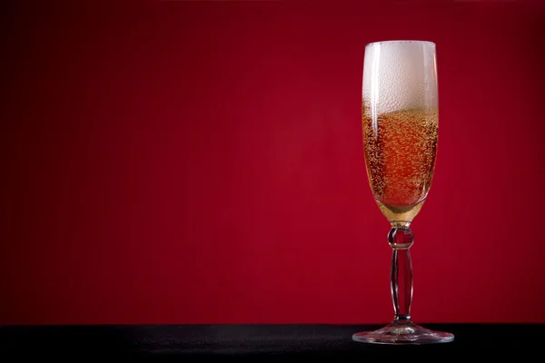 Бокал шампанского на красном фоне — стоковое фото