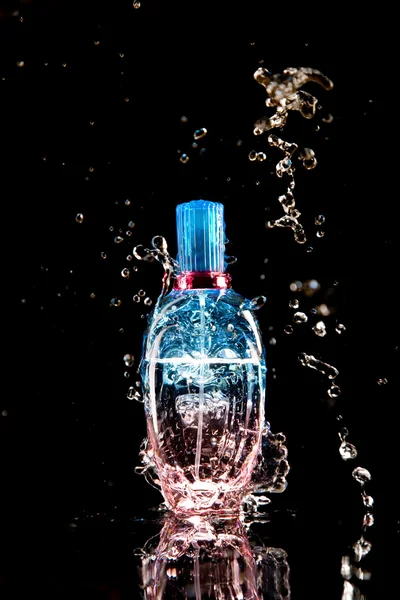 Botella de perfume con salpicaduras de agua — Foto de Stock