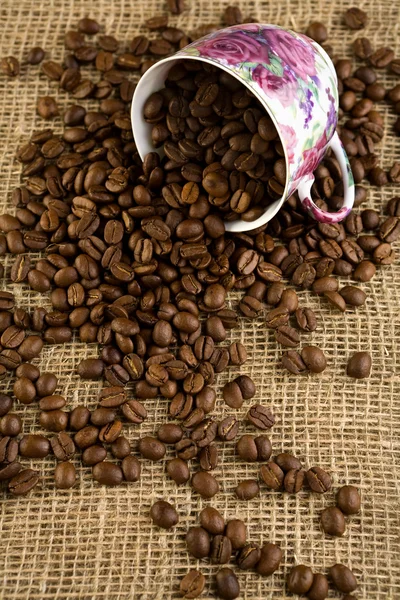 Cup och kaffe flinar på säckväv — Stockfoto