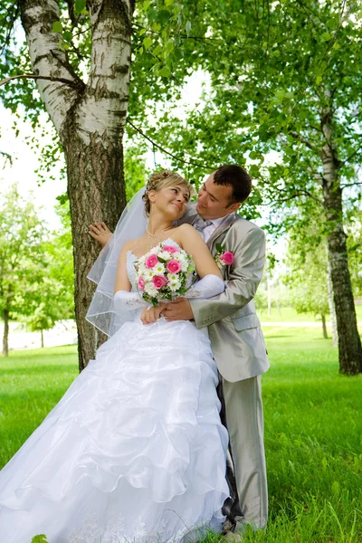 De bruidegom en de bruid in de buurt van een boom — Stockfoto