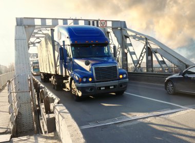 truck on bridge with cars on the bridge. 