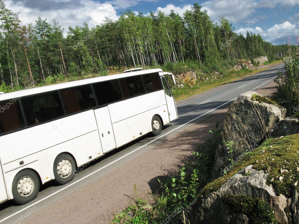 a large white car on a road in a beautiful landscape 