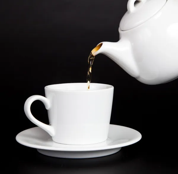 Verser le thé de la théière dans la tasse — Photo