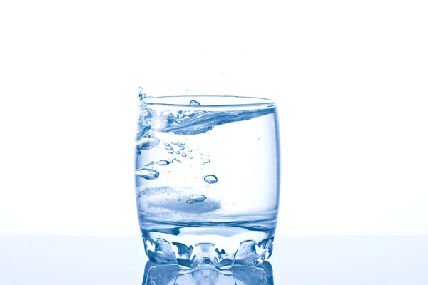 Gelo salpicando em um copo fresco de água — Fotografia de Stock