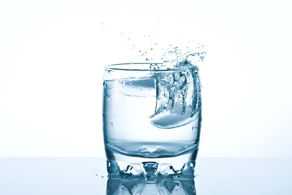 Salpicaduras de hielo en un vaso de agua fría — Foto de Stock